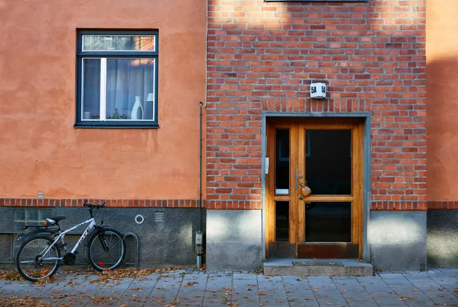 Enkel träport till flerbostadshus med röd tegelfasad på Domkyrkoesplanaden. Foto: Lasse Fredriksson.
