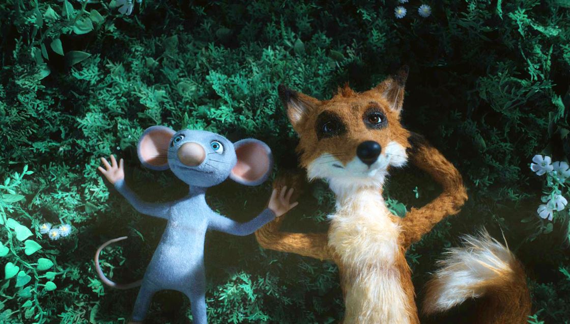 På en grön bädd av växter ligger två figurer som ser ut att vara tillverkade av tyg och päls. Till vänster en blå råtta och till höger en brun räv. De ligger båda på rygg med händerna utsträckta eller under huvudet.