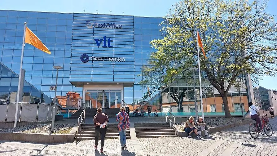 Stadsvandring om postmodernismen med VLT-husets glasfasad i bakgrunden och guiderna i förgrunden.