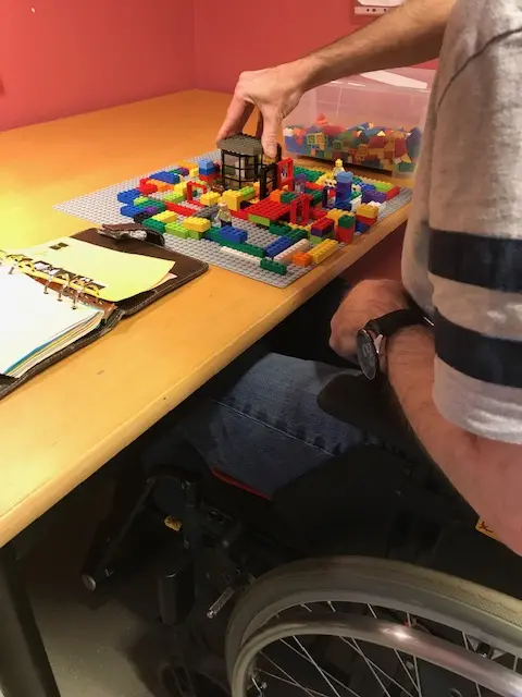 Person i rullstol bygger lego. 