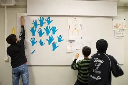 Pojkar som sätter upp papper på tavlan i ett klassrum.