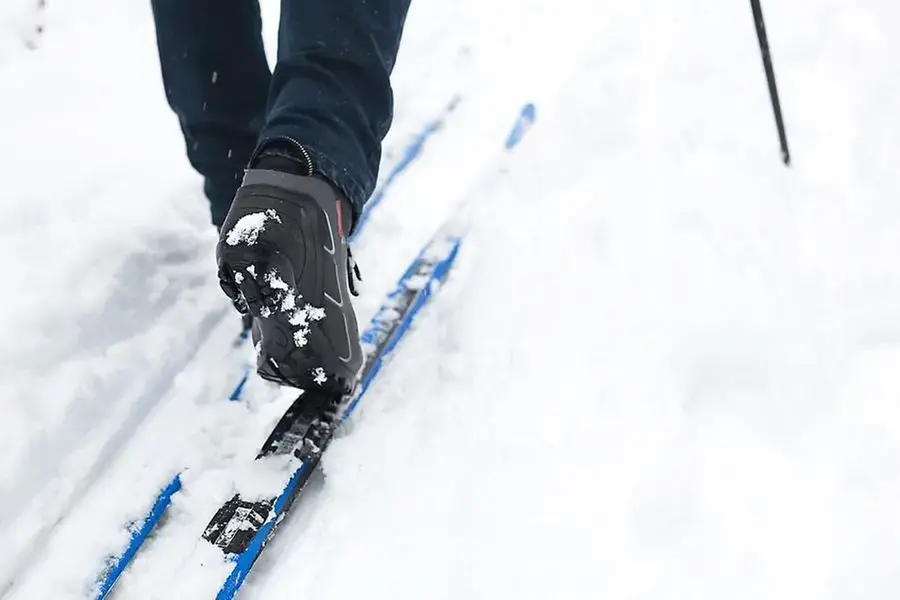 Åkares ben med pjäxor och skidor i snö